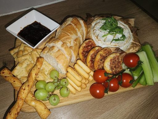 Gooey baked camembert served with bread, crackers and fruits. Baked Camembert